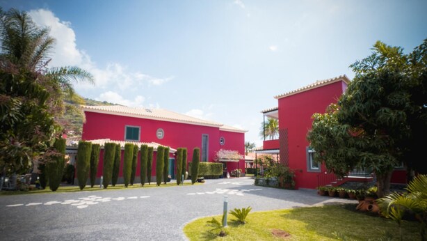 Un edificio rojo con entrada pavimentada y césped cuidado.