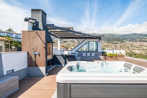 Una azotea moderna con un jacuzzi, una zona de estar y vistas a un pueblo en la ladera.