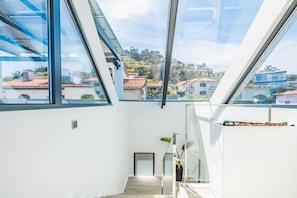Enjoy the airy feel of this spacious room with a high ceiling and skylight, featuring a staircase and a potted plant.