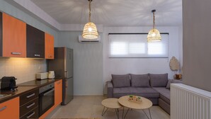 Une cuisine moderne avec des meubles de couleur orange, un coin repas avec deux tables rondes et un canapé gris dans l’espace de vie.