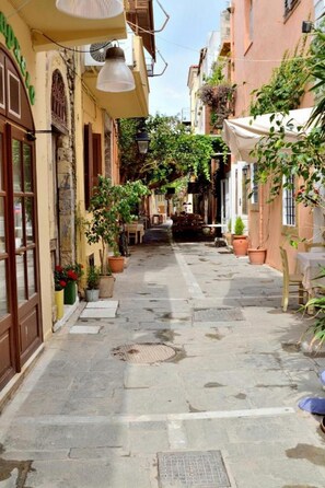 A narrow street with buildings on either side, outdoor seating, and potted plants. - Katrina Studio 3 With Balcony (Rethymno)