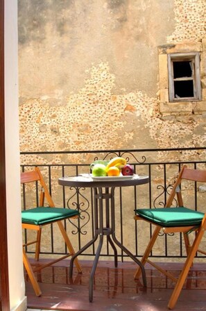 A small outdoor seating area with a table and two chairs, a window, and a wall with peeling paint. - Katrina Studio 3 With Balcony (Rethymno)