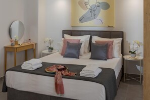 A modern hotel room with a large bed, two bedside tables, a mirror, and a painting on the wall. - Myra Mare White Suite by Estia (Heraklion)