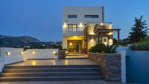 Una moderna casa a due piani con facciata in pietra, un portico coperto e una scala che conduce all'ingresso.