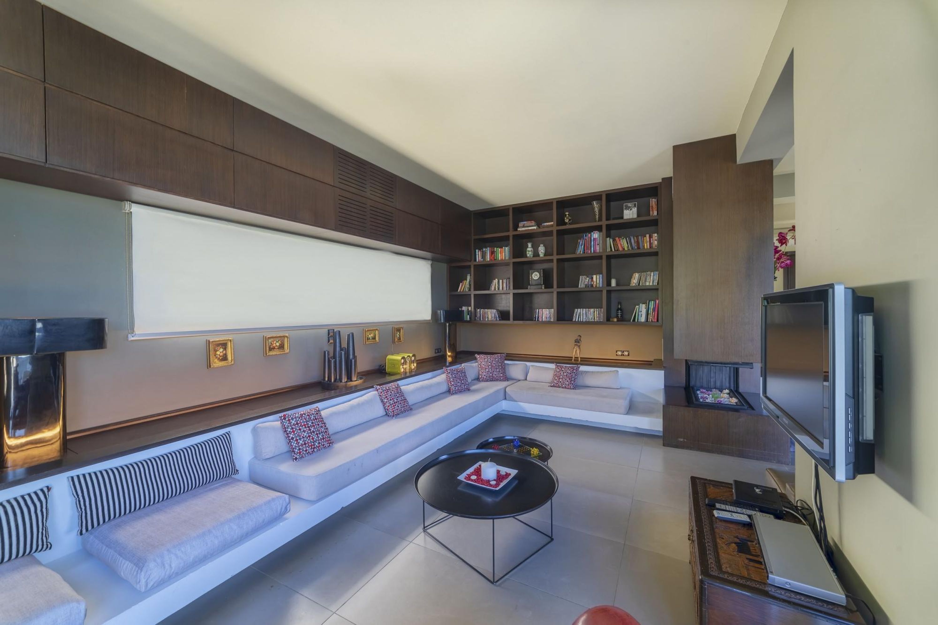 A modern living room with a sectional sofa, a flat-screen TV, a bookshelf, and a coffee table.