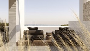 Un área de estar moderna al aire libre con vista al océano, que incluye una pérgola de madera, un sofá y una mesa de centro.