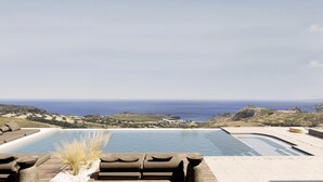 Zona de piscina con sillones de descanso y vista al mar.