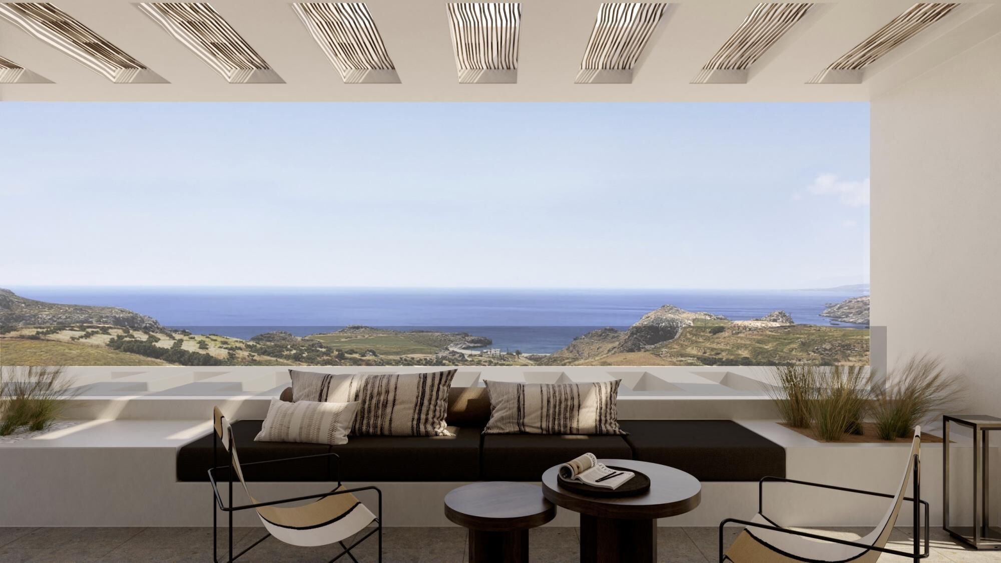 Un área de estar exterior moderna con un sofá, sillas y una mesa, con vistas a un paisaje costero.