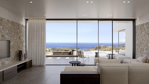 Un moderno salón con un amplio ventanal corredera que da a un balcón con vistas al mar.