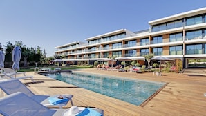Um hotel moderno com área de piscina, espreguiçadeiras e guarda-sóis.