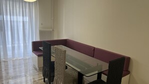 A dining area with a glass table, cushioned benches, and a radiator.