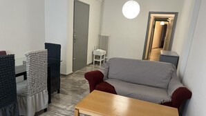 A living room with a sofa, two chairs, a coffee table, a radiator, and a door.