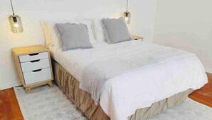 Un dormitorio con cama, mesitas de noche y alfombra.