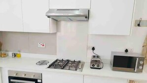 Una cocina moderna con armarios blancos, estufa a gas, tostadora, microondas y horno.