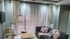 A modern living room with a dark grey sofa, a wooden coffee table, and a glass side table with decorative items. - Posh 3 Bed Guesthouse in Hillside With Pool - 2039 (Bulawayo)