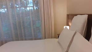 Un lit bien fait, avec du linge de lit blanc, dans une chambre d’hôtel.