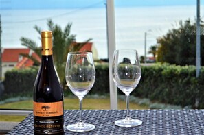 Una bottiglia di vino e due bicchieri su un tavolo con vista sul mare e sugli edifici sullo sfondo.