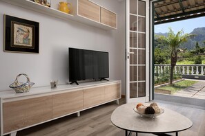 A modern living room with a flat-screen TV, a wooden cabinet, a decorative basket, and a table with decorative items. - Vila do Largo A by Homie (São Vicente)