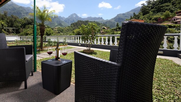 A terrace with wicker furniture, a bottle of wine, and glasses on a table. - Vila do Largo A by Homie (São Vicente)
