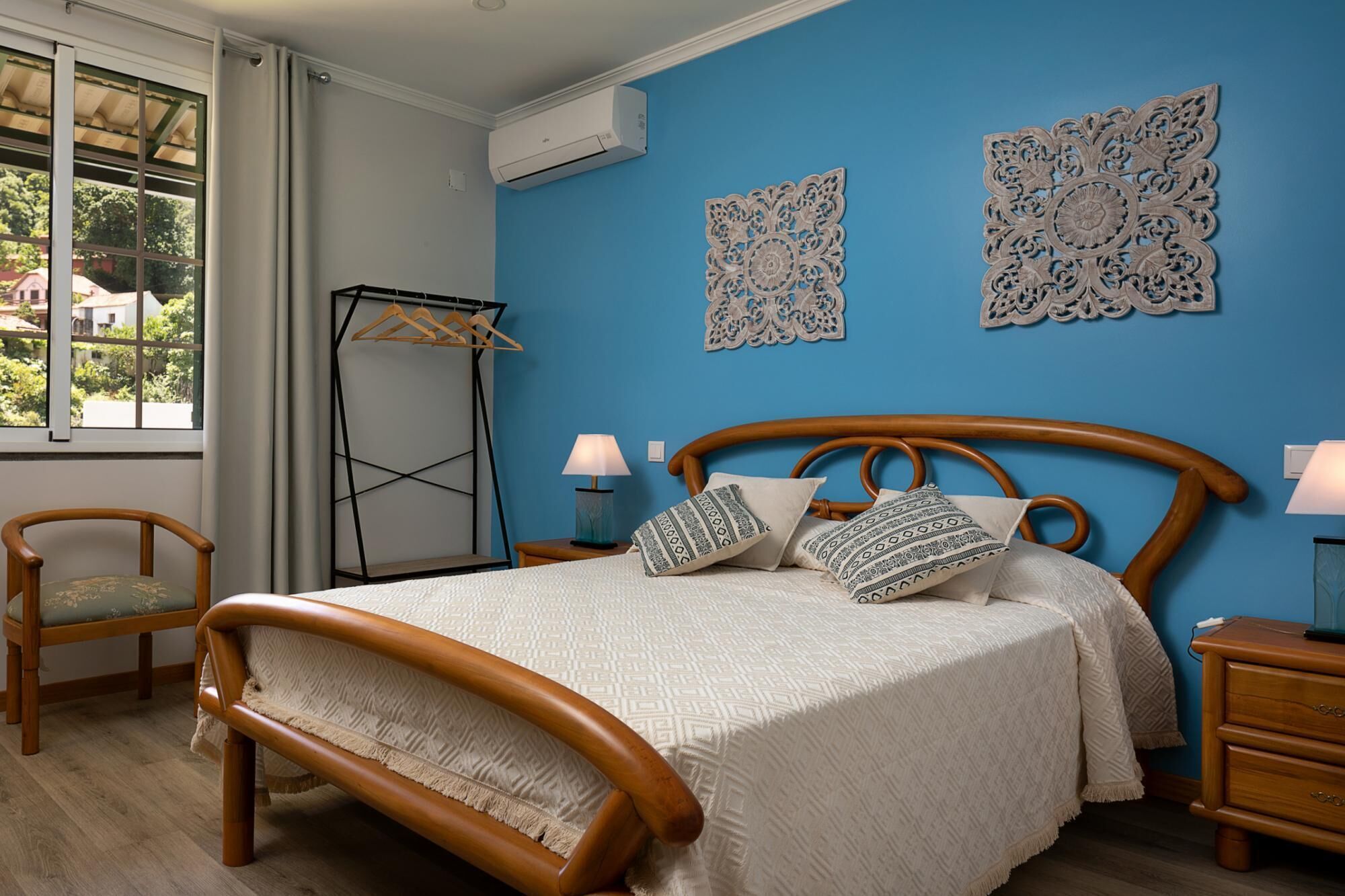 A bedroom with a wooden bed, a hanging clothes rack, and decorative wall art.