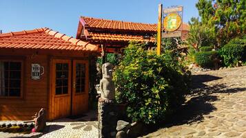 Un edificio de madera con techo de tejas, una estatua de piedra y un cartel.
