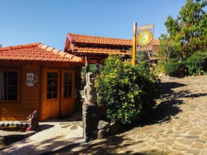A wooden building with a tiled roof, a stone statue, and a signboard.