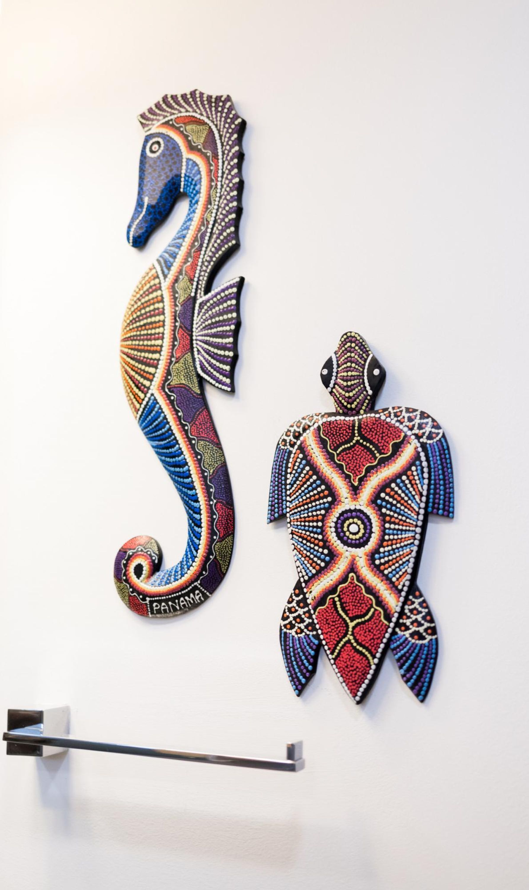 Two wall-mounted decorative pieces, one depicting a seahorse and the other a stylized human figure, both adorned with intricate beadwork patterns.