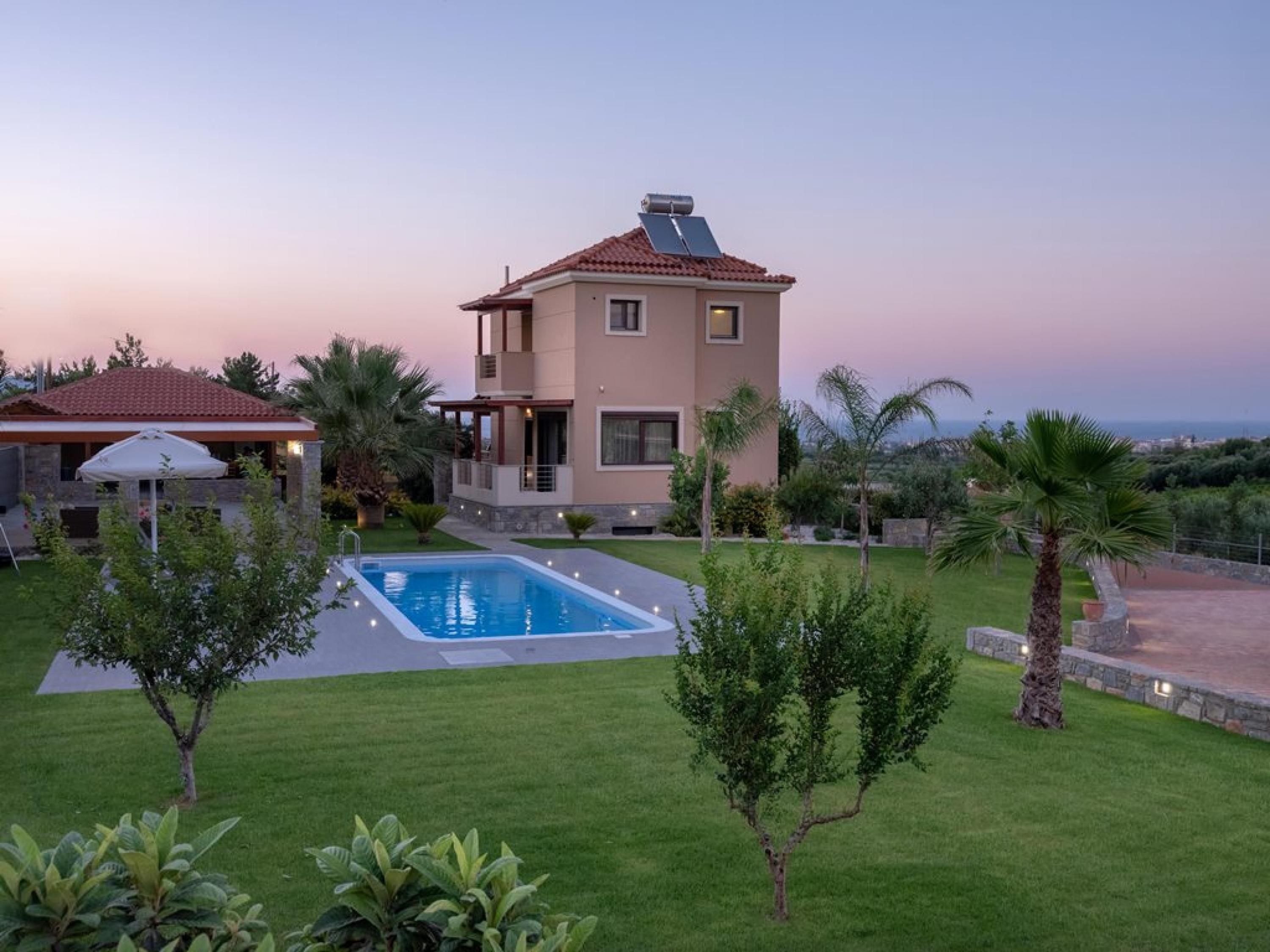 Une maison à deux étages avec une piscine, entourée d’une pelouse bien entretenue et de palmiers.