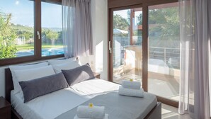 A modern bedroom with a large bed, two windows, and a sliding glass door leading to a balcony. - Villa David With Private Pool (Malevizi)