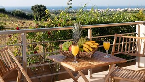 A wooden table with a fruit basket and two glasses of orange juice on a balcony with a view of the countryside. - Villa David With Private Pool (Malevizi)