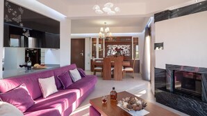 A modern living room with a purple sofa, a wooden coffee table, and a fireplace. - Villa David With Private Pool (Malevizi)