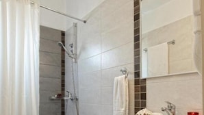 Une salle de bain équipée d’une douche, de toilettes, d’un lavabo et d’un miroir.