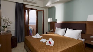 Une chambre d’hôtel avec un lit, une table de chevet, une lampe, une fenêtre avec des rideaux et une vue sur la mer.