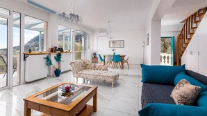 A spacious living room with a sofa, coffee table, and a dining area with chairs. - Olive Tree Villa by Estia (Corfu)