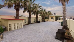 A courtyard with palm trees, a gravel ground, and a building with a red roof. - Yialos Cohili Beach Residence by Estia (Hersonissos)