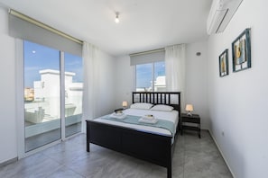 Relax in this serene bedroom with a large bed, sliding glass door to a balcony, and air conditioning for a comfortable stay.