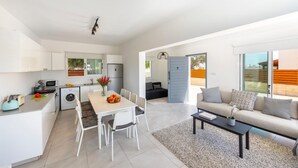 A modern apartment with a kitchen, dining area, and living room. It features a dining table with chairs, a sofa, and a coffee table. - Ayia Napa Marina Vibes (Sotira)