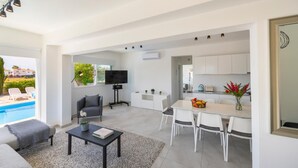 A modern living room with a pool view, a dining area, and a kitchen. - Ayia Napa Marina Vibes (Sotira)