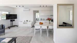 A modern, open-plan living space with a dining area, kitchen, and a large mirror. - Ayia Napa Marina Vibes (Sotira)