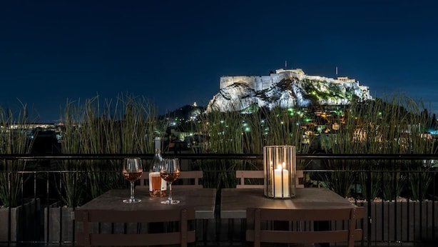 A table with two chairs and a candle, overlooking a historic building at night. - Executive 2 bdr Suite in Plaka - Acropolis View (Athens)