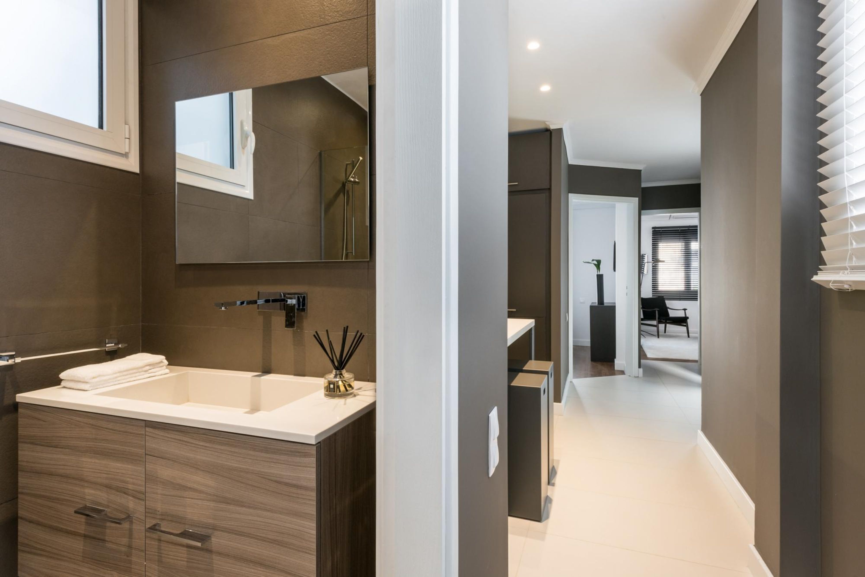 A modern bathroom with a large sink, mirror, and dark wood cabinetry.