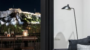 A modern living room with a view of a historic building at night. - Executive 2 bdr Suite in Plaka - Acropolis View (Athens)