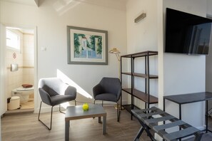 A modern living room with a sofa, a coffee table, a TV, and a painting on the wall. - Downtown Cocoon With Roof Deck (Athens)