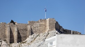 A historic stone fortress with a flagpole, stone walls, and a rocky terrain. - Downtown Cocoon With Roof Deck (Athens)