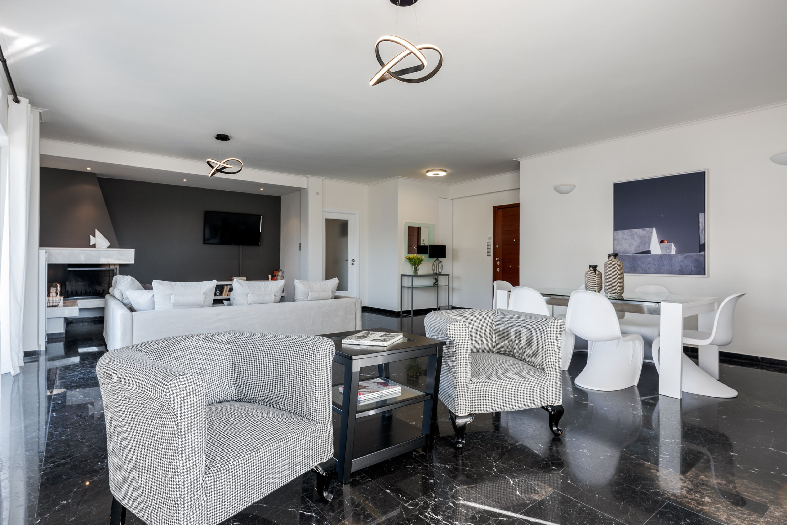 A modern living room with a sofa, two armchairs, a coffee table, and a dining area with a table and chairs.