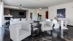 Una sala moderna con sofá, dos sillones, una mesa de centro y un comedor con mesa y sillas.