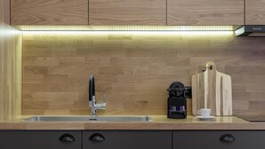 A modern kitchen with a wooden backsplash, a stainless steel sink, a coffee maker, and a cutting board. - 3bdr Modern Design Bright Interiors in Plaka (Athens)