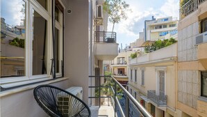 A balcony with a black chair, a railing, and a view of neighboring buildings. - 3bdr Modern Design Bright Interiors in Plaka (Athens)