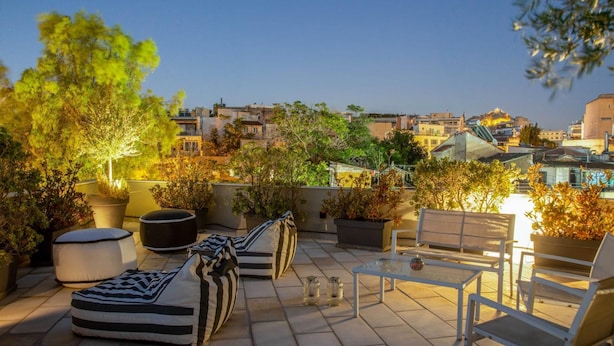 Terraza en la azotea con asientos, plantas en macetas y vistas a la ciudad.