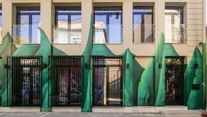 Fachada de edificio con tres estructuras verdes y formas onduladas y portones negros.